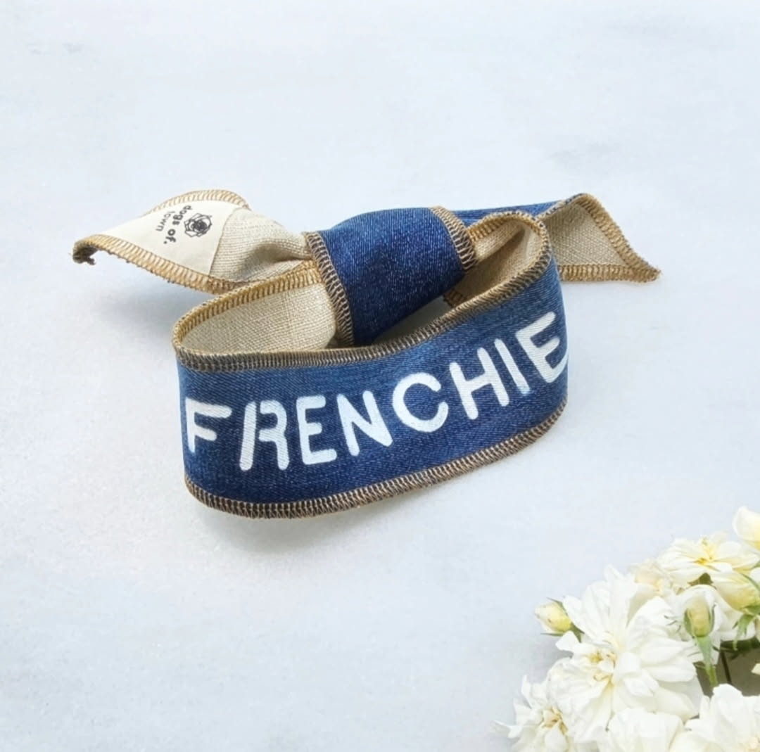 Denim dog scarf with 'FRENCHIE' on a light background with white flowers.